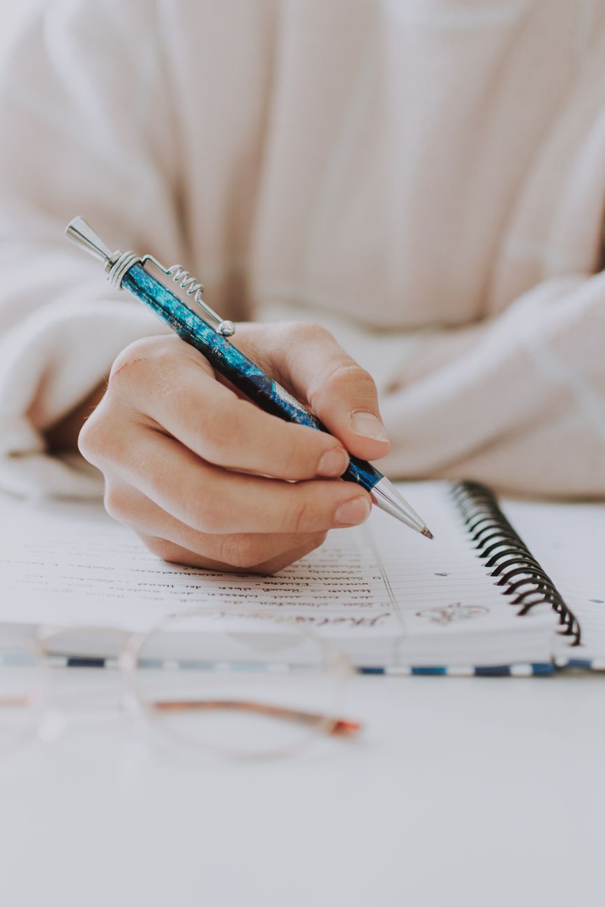 woman with pen writing notes in notepad